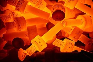 Heated metal billets glowing orange, ready for forging in high-temperature processes
