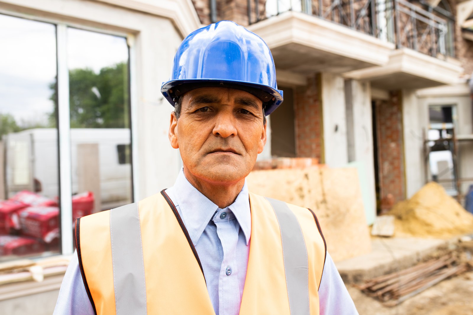 Portrait of joyful indian american man architect at building site looking at camera
